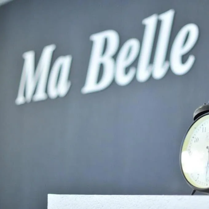 Uzraksts „Ma&nbsp;Belle” uz tumši pelēkas sienas salonā